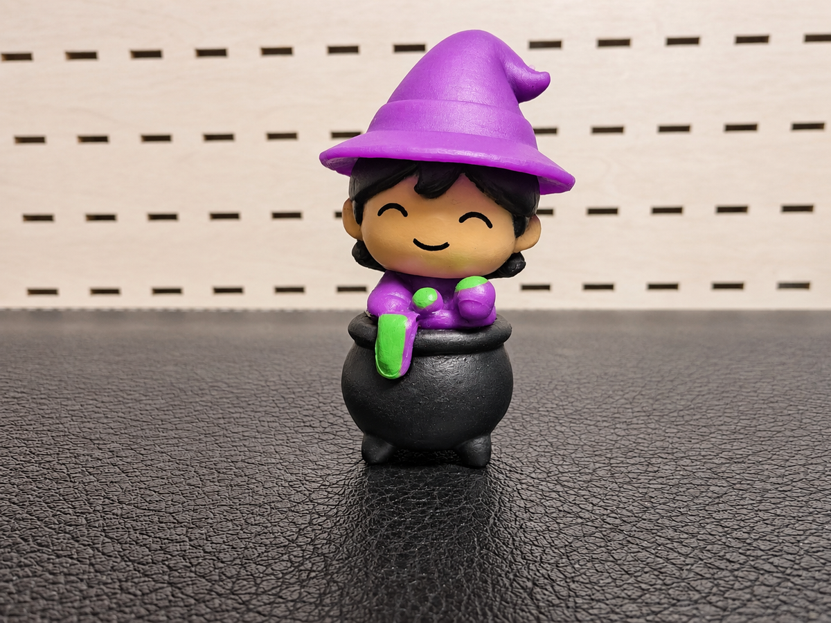 Figura decorativa de brujita morada con caldero negro
