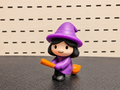 Figura decorativa de brujita morada con escoba naranja