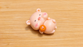 Figura cerdito tumbado con un caramelo naranja