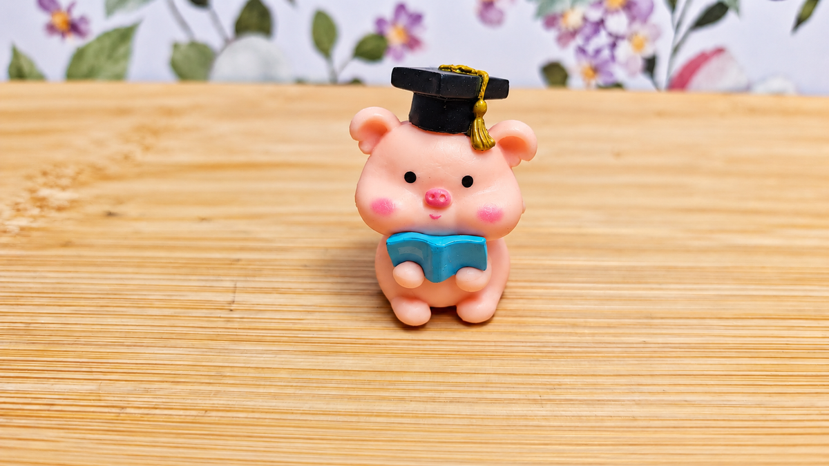 Figura cerdito graduado con birrete y libro azul