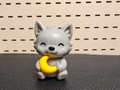 Figura decorativa de gatito gris sosteniendo una luna amarilla