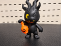 Figura decorativa de monstruo negro con calabaza naranja