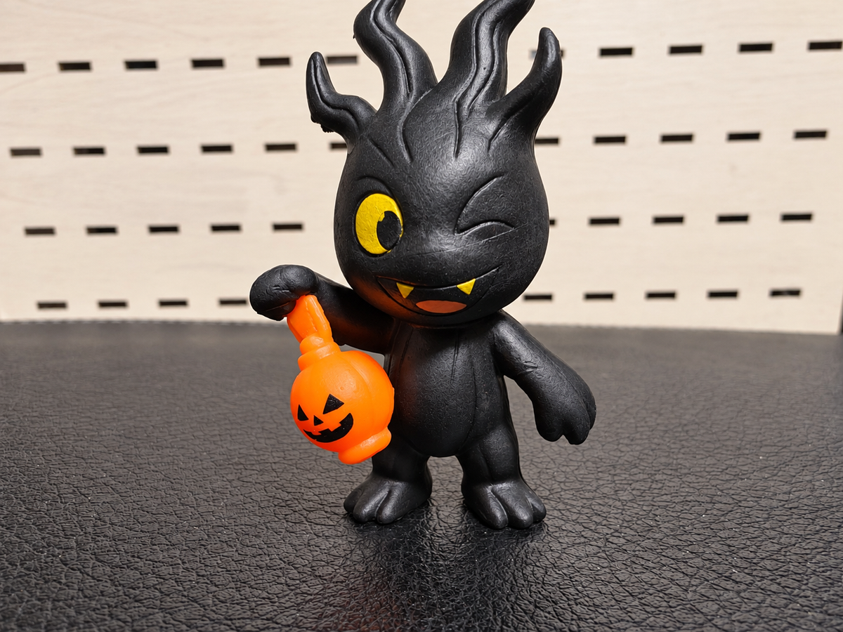 Figura decorativa de monstruo negro con calabaza naranja