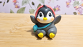 Figura de pingüino sentado con capucha roja