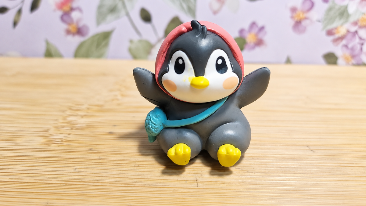 Figura de pingüino sentado con capucha roja