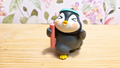 Figura de pingüino deportista con cinta turquesa