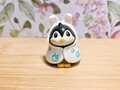 Figura de pingüino con disfraz de conejo blanco