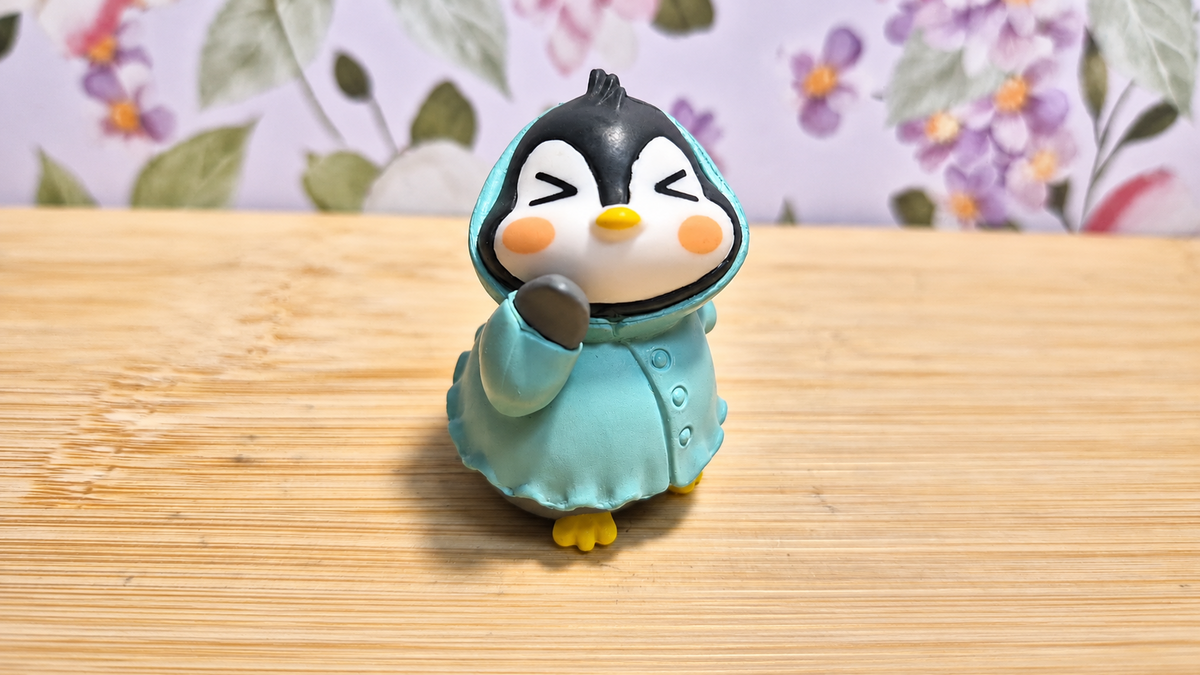 Figura de pingüino con impermeable turquesa